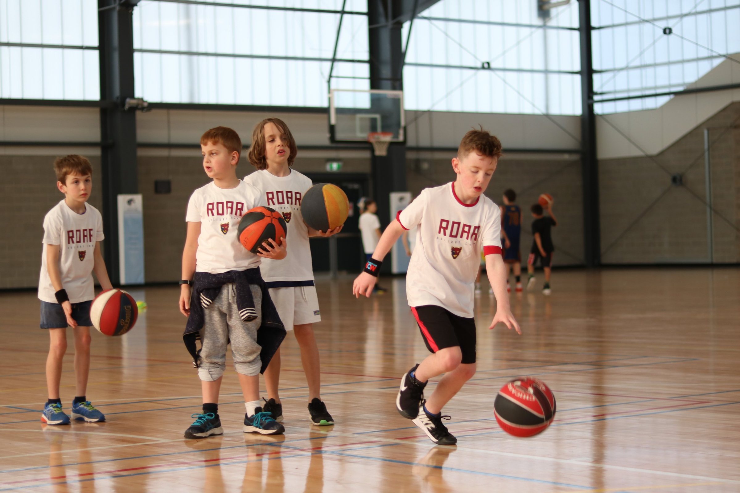 Kids dribbling on court at an Aussie Hoops session